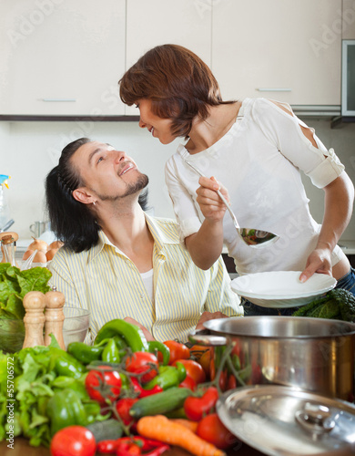 Photo: Handsome man and beautiful woman with vegetables in the kitchen Handsome man and beautiful woman with vegetables in the kitchen