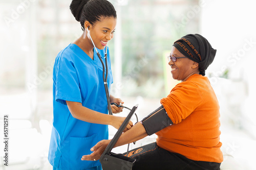 Photo: african nurse checking senior patient's blood pressure african nurse checking senior patient's blood pressure