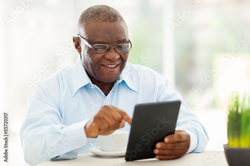 Photo: senior african american man using tablet computer at home senior african american man using tablet computer at home