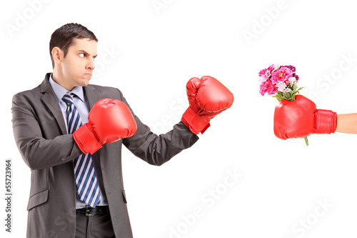 Photo: Angry man with boxing gloves hitting a hand with boxing glove Angry man with boxing gloves hitting a hand with boxing glove