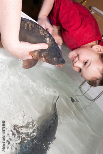 Photo: women with son touching christmas carp women with son touching christmas carp