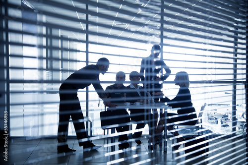 Photo: silhouettes of business people through the blinds silhouettes of business people through the blinds