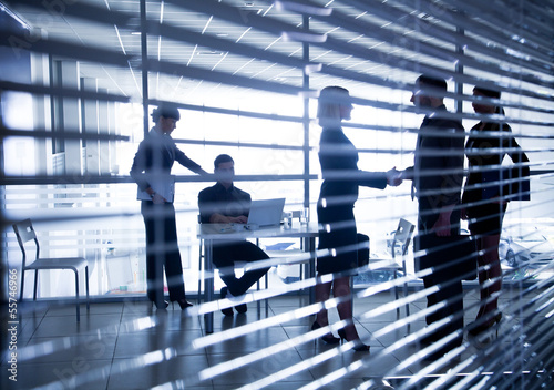 Photo: silhouettes of business people through the blinds silhouettes of business people through the blinds