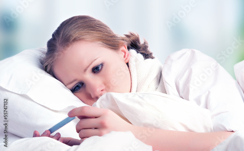 Photo: Woman with thermometer sick colds, flu, fever in bed Woman with thermometer sick colds, flu, fever in bed