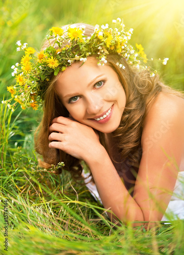 Photo: beautiful woman in wreath of flowers lies in the green grass out beautiful woman in wreath of flowers lies in the green grass out