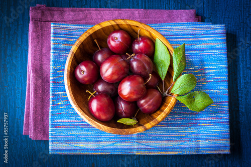 Photo: Plums in a wooden bowl on a vintage wooden background Plums in a wooden bowl on a vintage wooden background