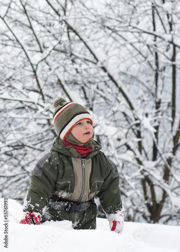 Photo: Child toddler standing and walking in deep snow in winter. Child toddler standing and walking in deep snow in winter.