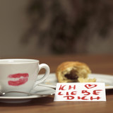 Photo : Tasse Kaffee mit Lippenstift Kussabdruck, angebissenes Croissant und ein lieber Zettel Tasse Kaffee mit Lippenstift Kussabdruck, angebissenes Croissant und ein lieber Zettel