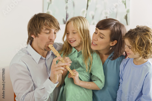 Photo: Familie im Wohnzimmer, der Vater spielt Blockflöte, Portrait Familie im Wohnzimmer, der Vater spielt Blockflöte, Portrait