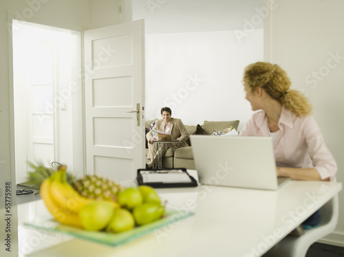 Photo: Junge Frau mit Laptop, Mann im Hintergrund Junge Frau mit Laptop, Mann im Hintergrund