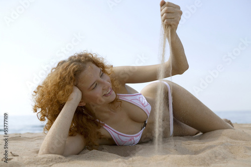 Photo: Junge Frau liegt am Strand, spielen mit Sand Junge Frau liegt am Strand, spielen mit Sand