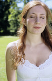 Photo : Junge Frau im weißen Kleid stehend im Garten, die Augen geschlossen, Nahaufnahme Junge Frau im weißen Kleid stehend im Garten, die Augen geschlossen, Nahaufnahme