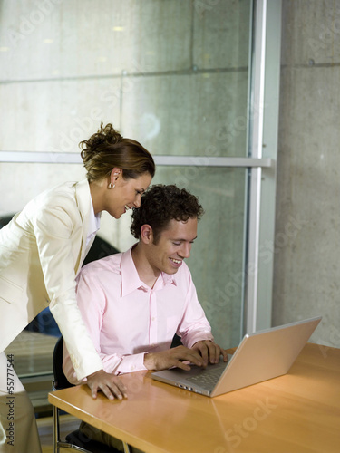 Photo: Mann und Frau im Büro, mit Laptop, lächelnd Mann und Frau im Büro, mit Laptop, lächelnd