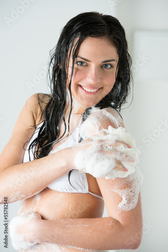 Photo: Young woman washing body with shower gel Young woman washing body with shower gel