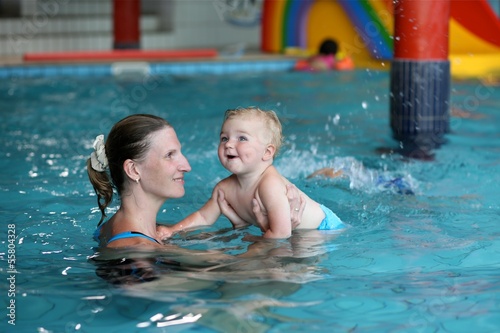 Photo: Young mother with cute baby training in swimming pool Young mother with cute baby training in swimming pool