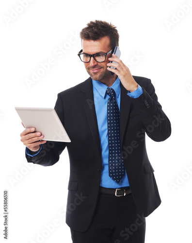 Photo: Busy businessman working on tablet and mobile phone Busy businessman working on tablet and mobile phone