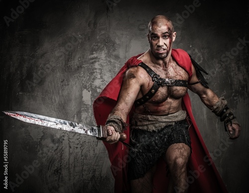 Photo: Wounded gladiator attacking with sword covered in blood Wounded gladiator attacking with sword covered in blood
