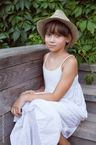 Photo: Cute girl in a hat sitting on the porch Cute girl in a hat sitting on the porch