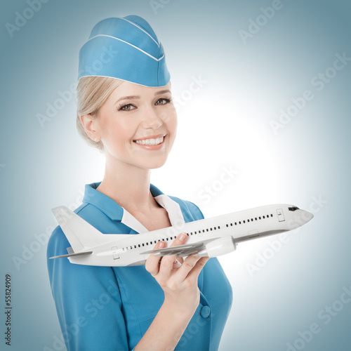 Photo: Charming Stewardess Holding Airplane In Hand. Charming Stewardess Holding Airplane In Hand.