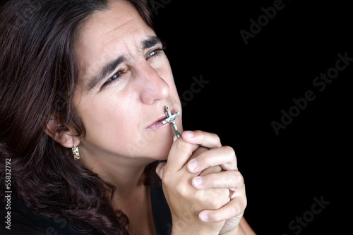Photo: Hispanic woman praying and kissing a crucifix Hispanic woman praying and kissing a crucifix
