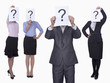 Photo: Four business people holding up paper with question mark, obscured face, studio shot Four business people holding up paper with question mark, obscured face, studio shot