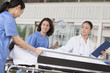 Photo: Female paramedics and doctor wheeling in a patient on a stretcher in front of the hospital Female paramedics and doctor wheeling in a patient on a stretcher in front of the hospital