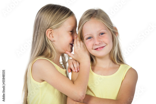 Photo: Blonde girl whispering to her sister Blonde girl whispering to her sister