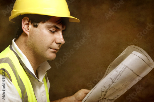 Photo: Male builder site foreman reading architectural industrial plans Male builder site foreman reading architectural industrial plans