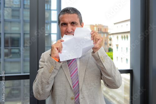 Photo: Uomo d'affari che strappa un foglio Uomo d'affari che strappa un foglio