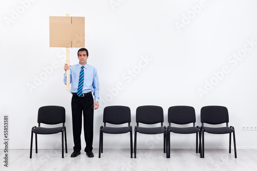 Photo: Lonely protesting businessman or employee holding placard Lonely protesting businessman or employee holding placard