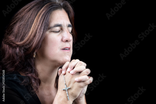 Photo: Portrait of an hispanic woman praying isolated on black Portrait of an hispanic woman praying isolated on black