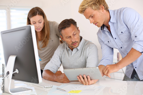 Photo: Business people in office working on desktop Business people in office working on desktop