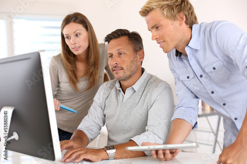 Photo: Business people in office working on desktop Business people in office working on desktop
