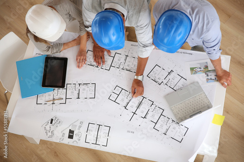 Photo: Upper view of architects working on blueprint Upper view of architects working on blueprint