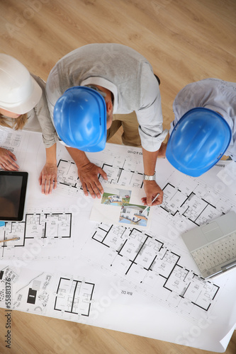 Photo: Upper view of architects working on blueprint Upper view of architects working on blueprint