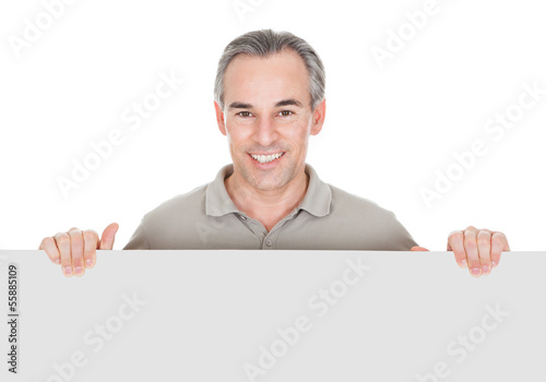 Photo: Happy Mature Man Standing Behind Placard Happy Mature Man Standing Behind Placard
