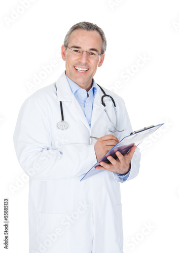 Photo: Happy doctor writing on clipboard Happy doctor writing on clipboard