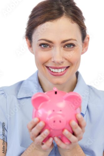 Photo: Businesswoman showing her piggy bank to camera Businesswoman showing her piggy bank to camera