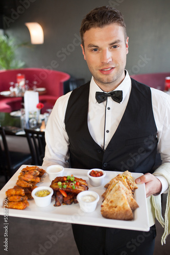 Photo: Handsome waiter serving appetizing finger food platter Handsome waiter serving appetizing finger food platter