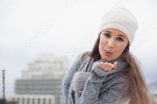 Photo: Pretty brunette with winter clothes on sending an air kiss to ca Pretty brunette with winter clothes on sending an air kiss to ca