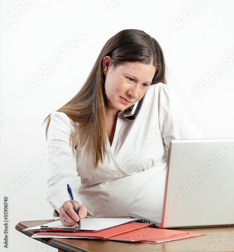 Photo: Pregnant Young Woman on Phone at Laptop at Work or Home Pregnant Young Woman on Phone at Laptop at Work or Home