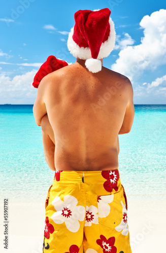 Photo: Couple in santa's hat on a beach at Maldives Couple in santa's hat on a beach at Maldives