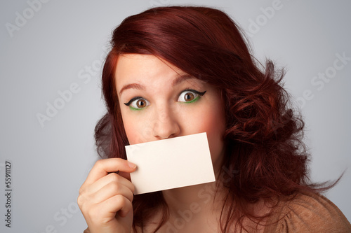 Photo: Cute girl holding white card at front of her lips with copy spac Cute girl holding white card at front of her lips with copy spac