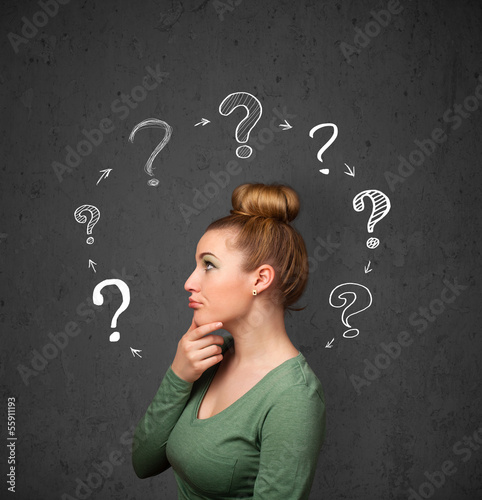 Photo: Young woman thinking with question mark circulation around her h Young woman thinking with question mark circulation around her h