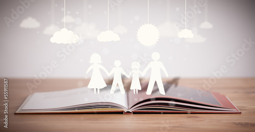Photo: Cardboard figures of the family on opened book Cardboard figures of the family on opened book