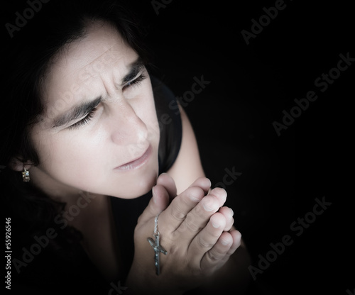 Photo: Emotional portrait of a latin woman praying isolated on black Emotional portrait of a latin woman praying isolated on black