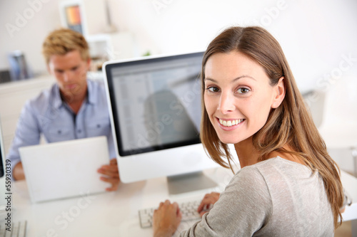 Photo: Portrait of smiling office worker in front of desktop Portrait of smiling office worker in front of desktop