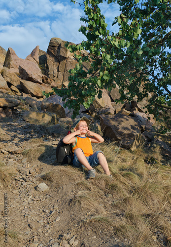 Photo: Playful little boy sitting waiting on a mountain Playful little boy sitting waiting on a mountain