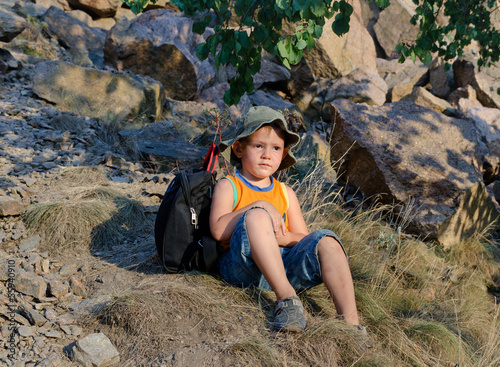 Photo: Little boy sitting on the ground at the mountains Little boy sitting on the ground at the mountains
