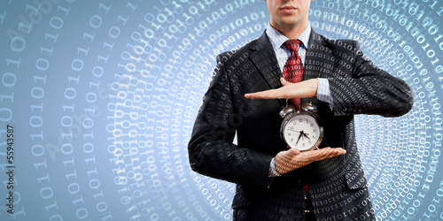 Photo: Business man holding alarmclock Business man holding alarmclock